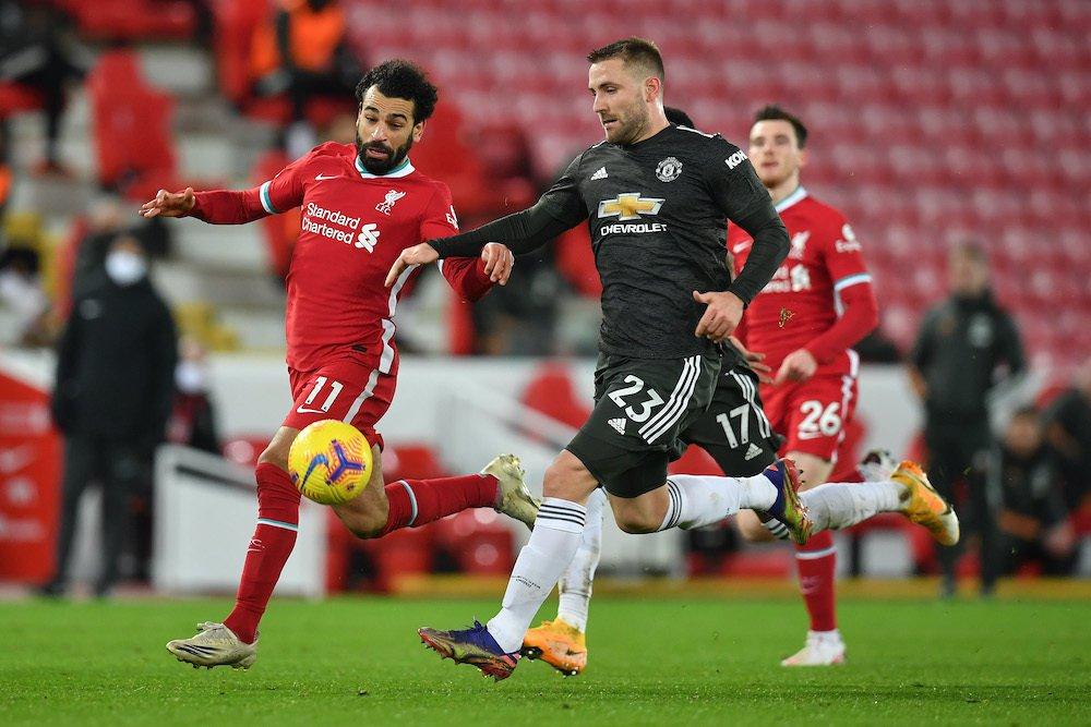 LIVERPOOL, ENGLAND - JANUARY 17: Luke Shaw of Manchester United  is put under pressure by Mohamed Salah of Liverpool during the Premier League match between Liverpool and Manchester United at Anfield on January 17, 2021 in Liverpool, England. Sporting stadiums around England remain under strict restrictions due to the Coronavirus Pandemic as Government social distancing laws prohibit fans inside venues resulting in games being played behind closed doors. (Photo by Paul Ellis - Pool/Getty Images)